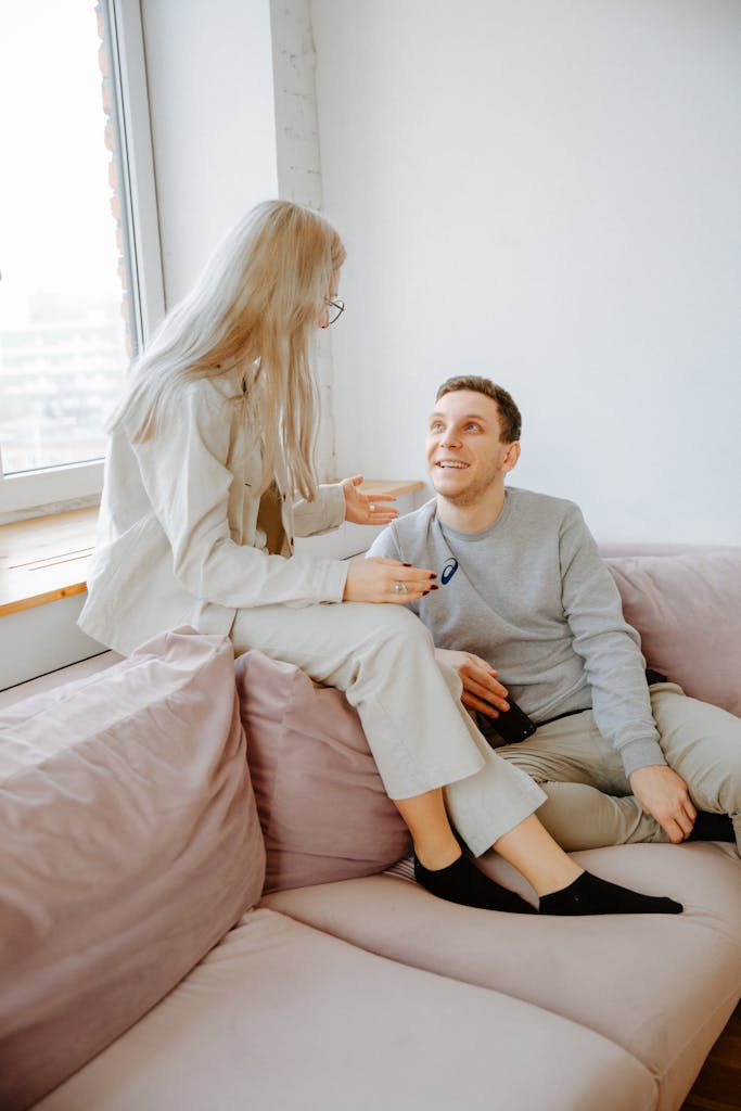 A young couple enjoys a warm conversation while relaxing on a sofa indoors.