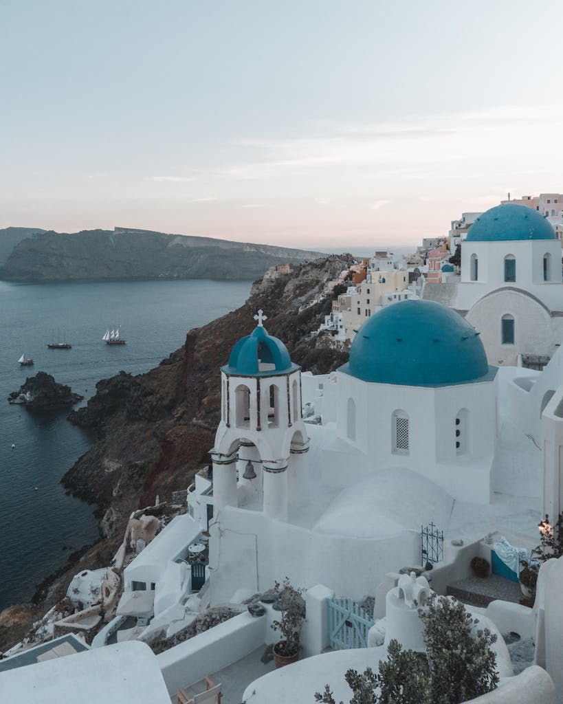 Experience the enchanting view of Santorini's blue domes at sunset, overlooking the Aegean Sea.