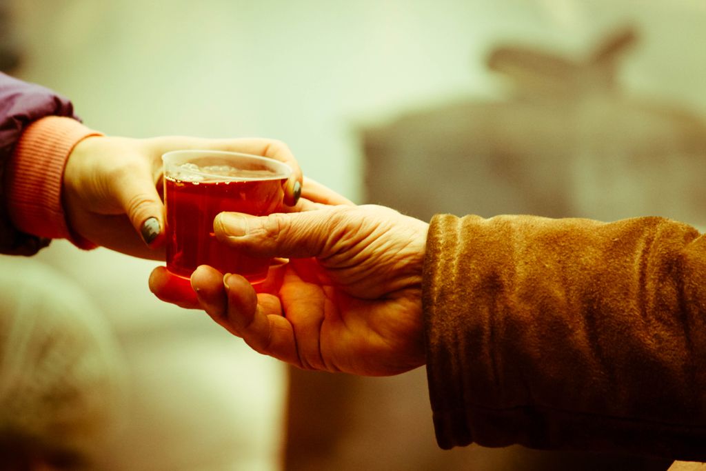 Two hands exchanging a hot drink outdoors in Kyiv, conveying warmth and connection.