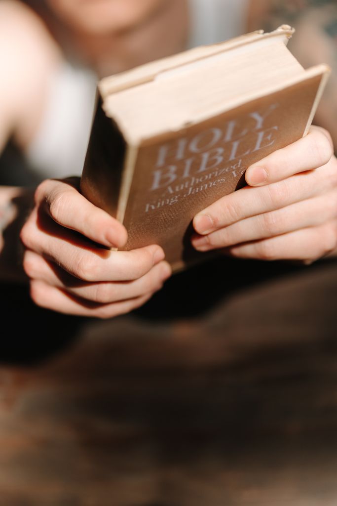 Focused close-up of hands holding an open Holy Bible, symbolizing faith and reflection.