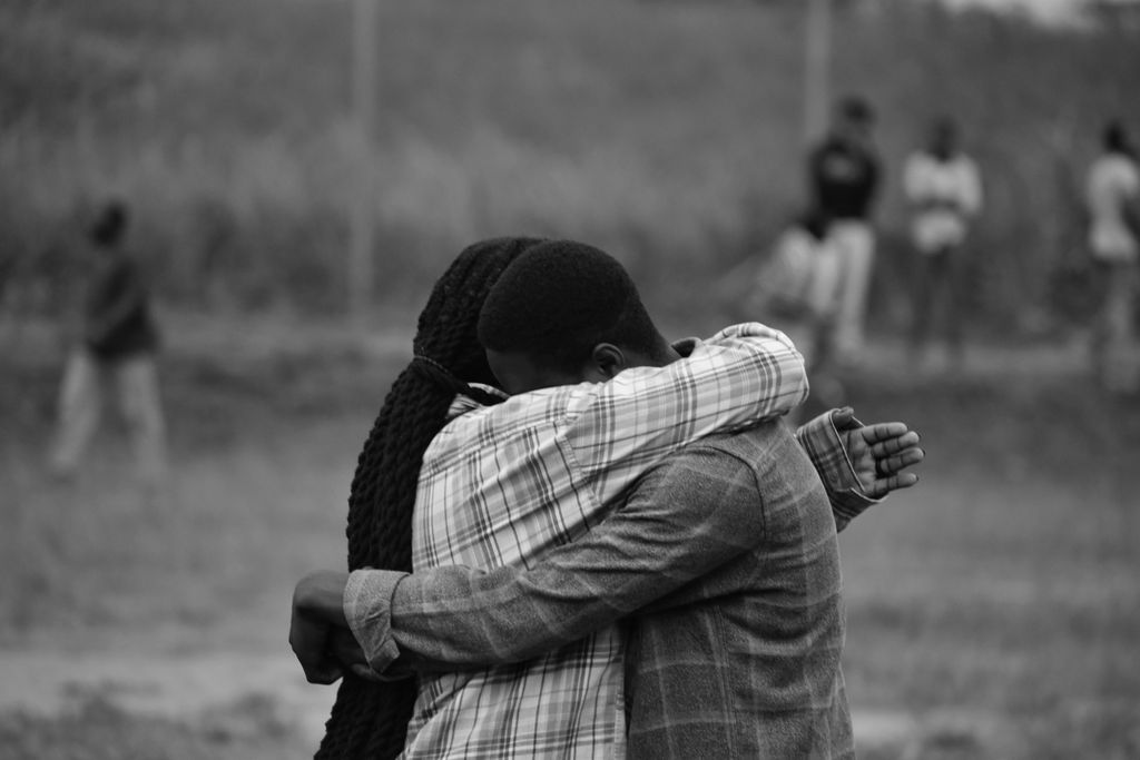 Two people hug in a heartfelt moment captured in monochrome outdoors.