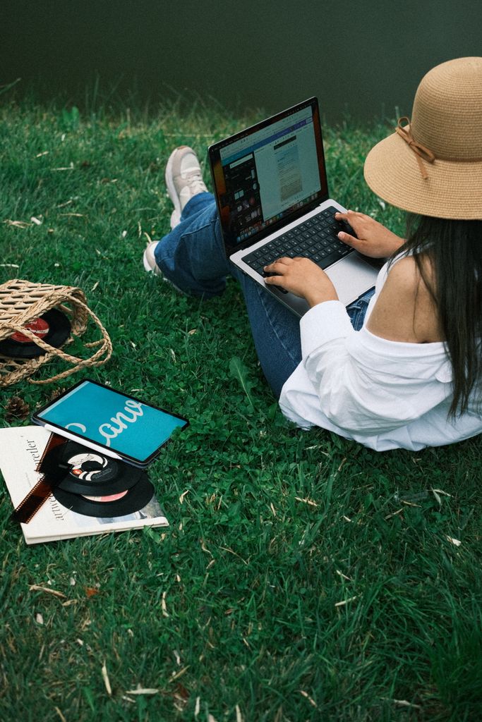 Young woman working on a laptop in the park, surrounded by nature and relaxation.
