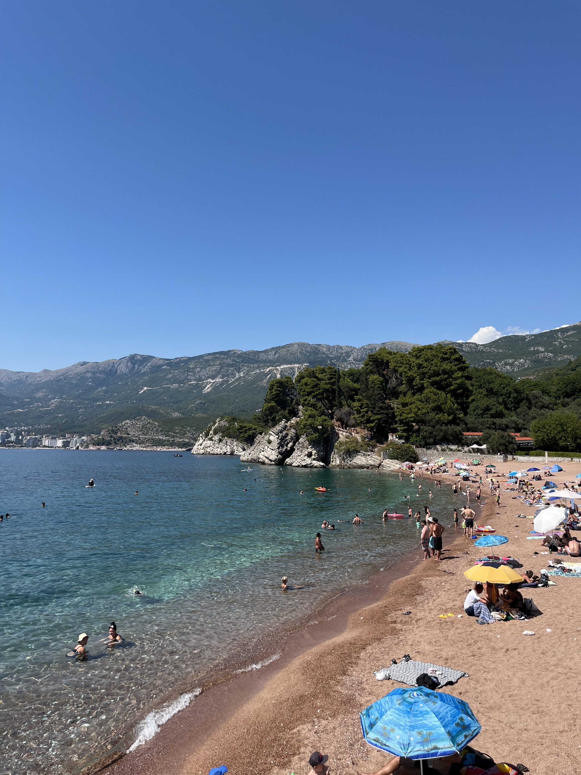 Golden sandy beach with vibrant waters of the Adriatic Sea at Sveti Stefan in Montenegro.