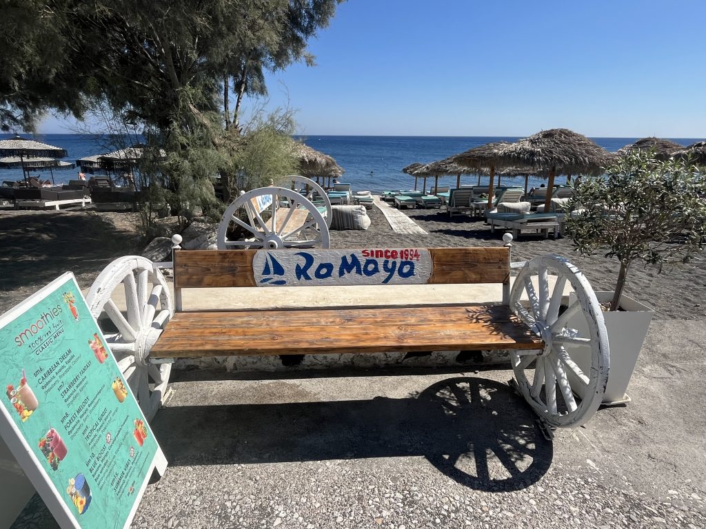 Perissa beach, Santorini. Bland sand beach with beach chairs and blue sea water of the Aegean Sea.