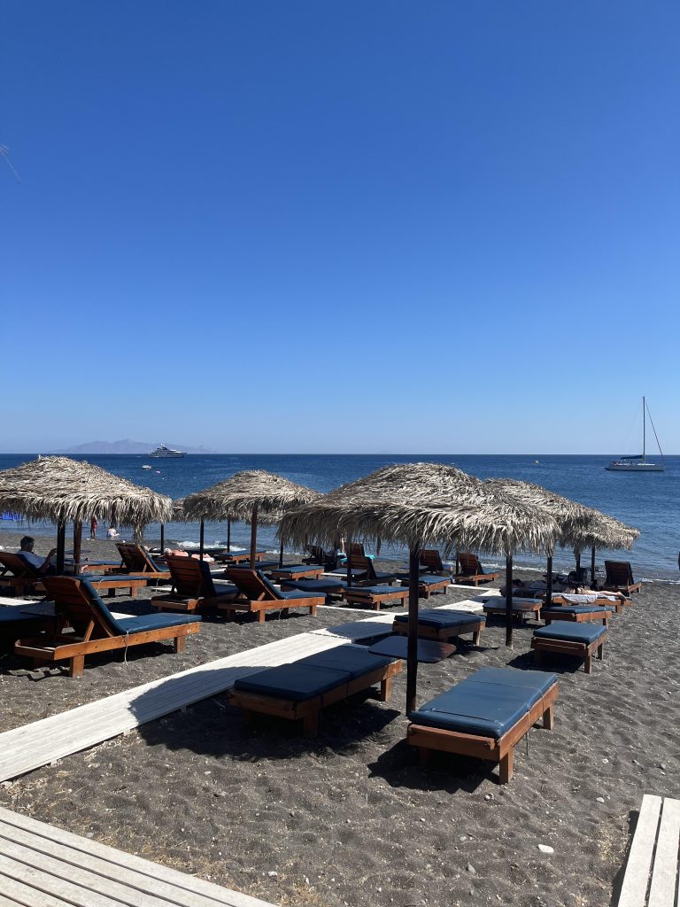 The black-sand beach in Perissa, Santorini with the deep blue sea waters of the Aegean Sea.