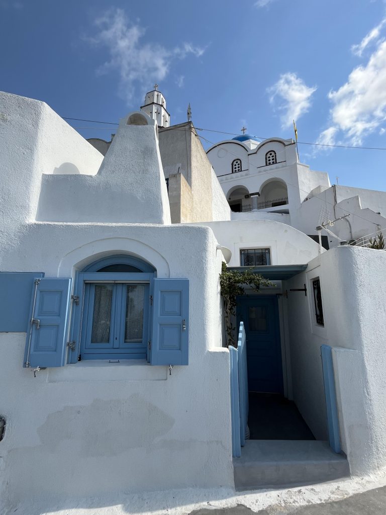 Pyrgos, Santorini. White-washed building with blue window and door frames in Greece.