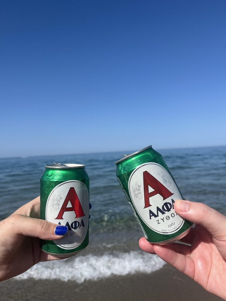 A couple enjoying a local Greek beer on Rethymno beach in Crete.