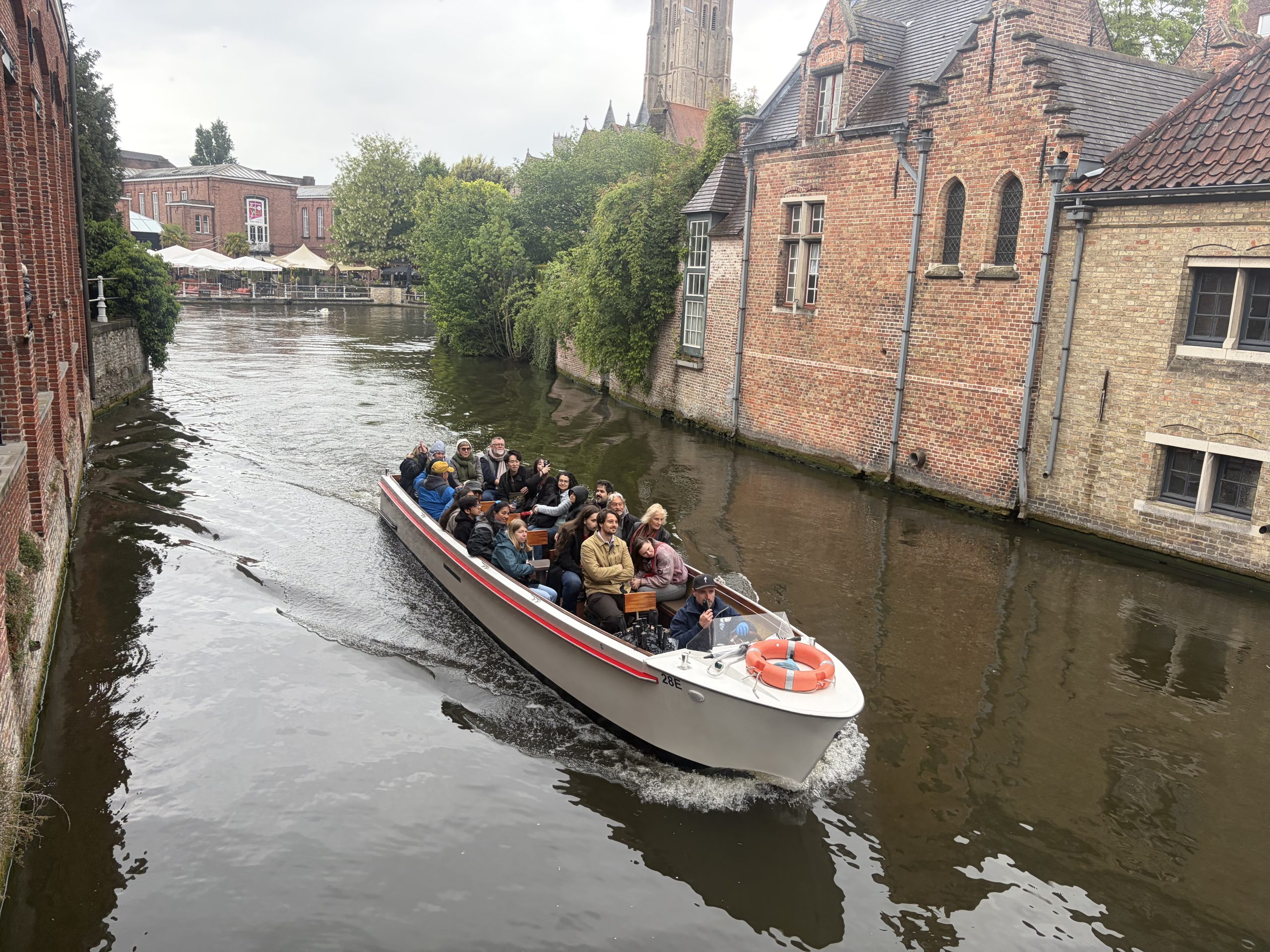 Boat in canal in Bruges surrounded by historic Flemish brick buildings.