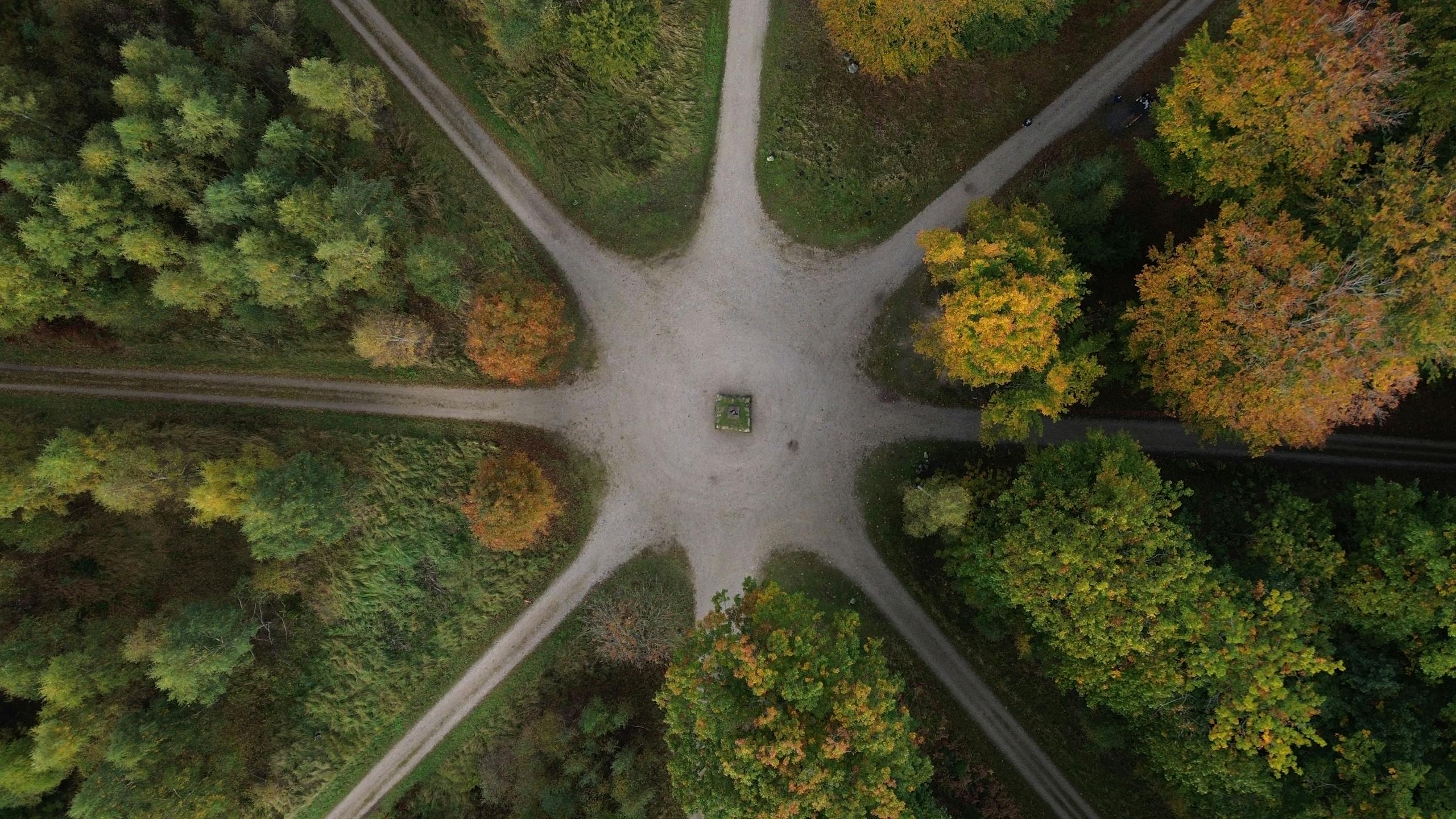 A stunning aerial view of a forest path intersection surrounded by autumn foliage.