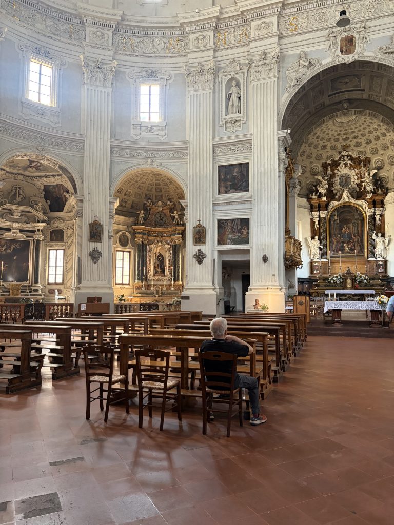A small, local church in Parma, Italy, where a man is praying to God.