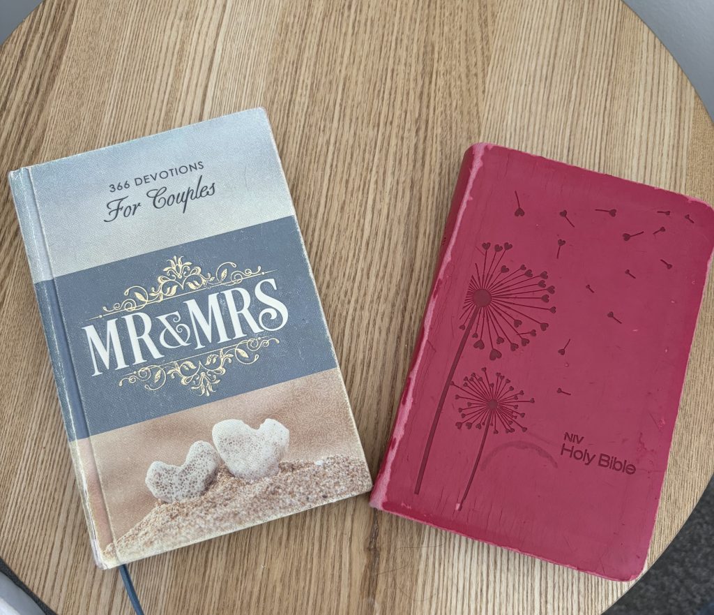 A Christian devotional book and the Holy Bible sitting on a wooden bedside table.