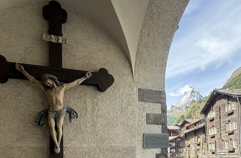 Jesus on a wooden cross in front of the Swiss Alps.