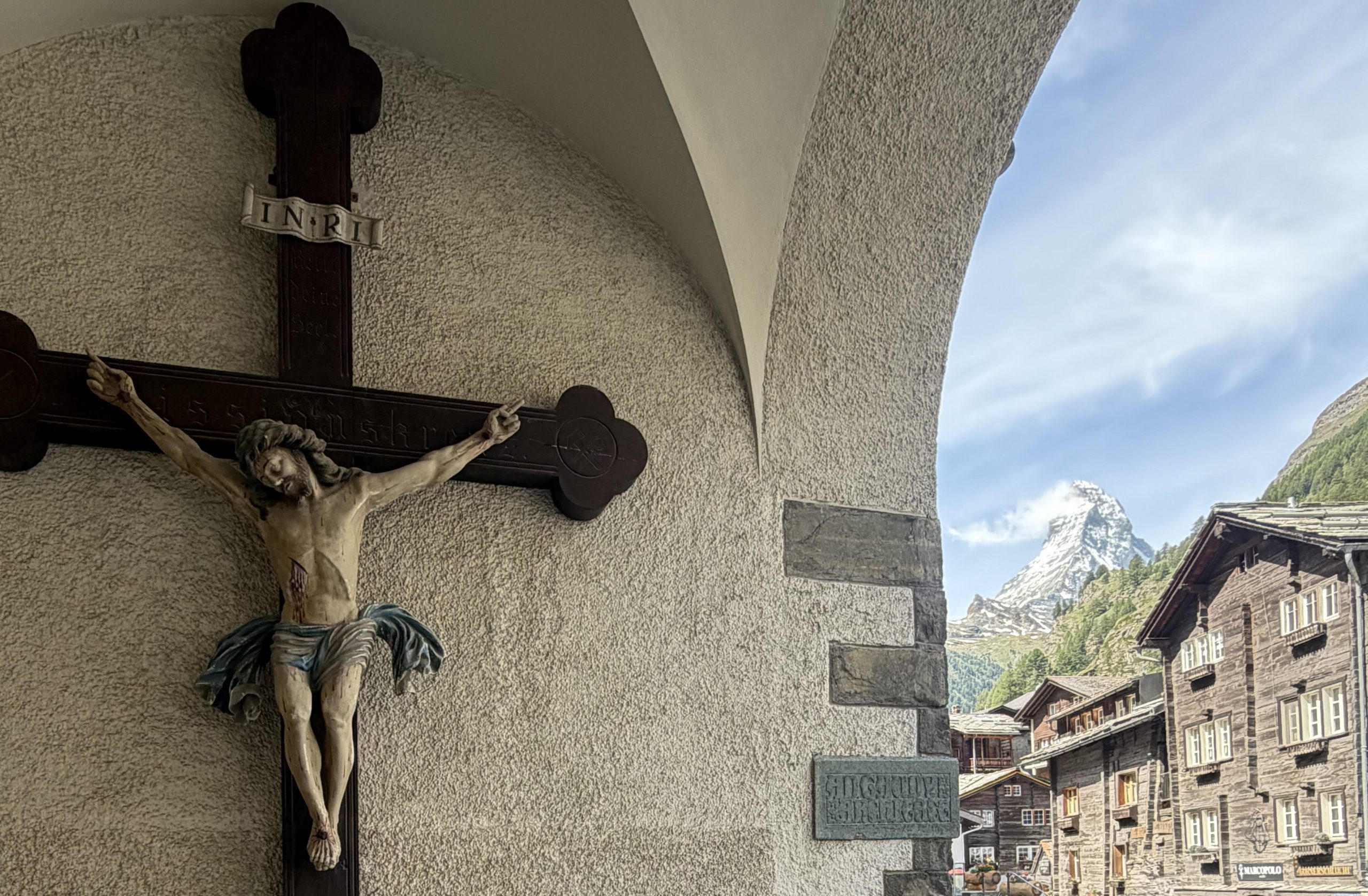 Jesus on a wooden cross in front of the Swiss Alps.