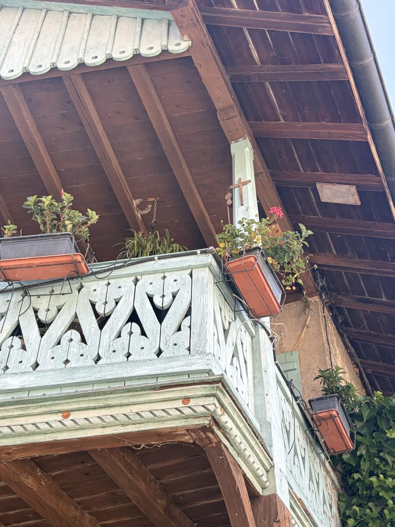 A wooden cross hung on a balcony in Europe, signifying the love and sacrifice of Jesus.