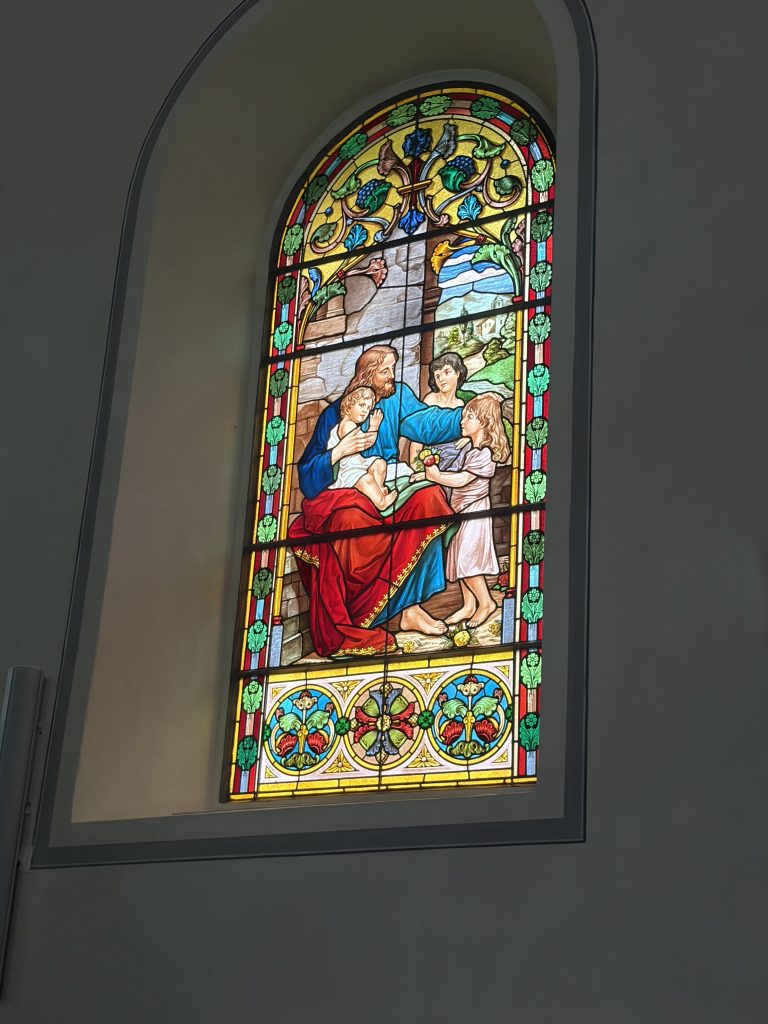 A stained glass window in a church in Switzerland. depicting the tender love of Jesus.