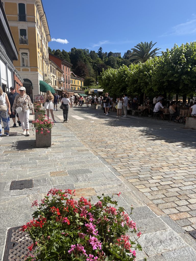 A busy street in Bellagio, Lake Como, lined with trees and villas.